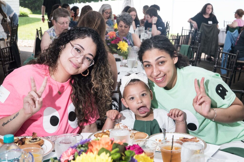 Three attendees smiling during breakfast. Award winner, Coco Black and her daughter.