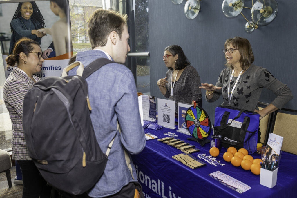 Attendees talking with exhibitors at an exhibitor table.