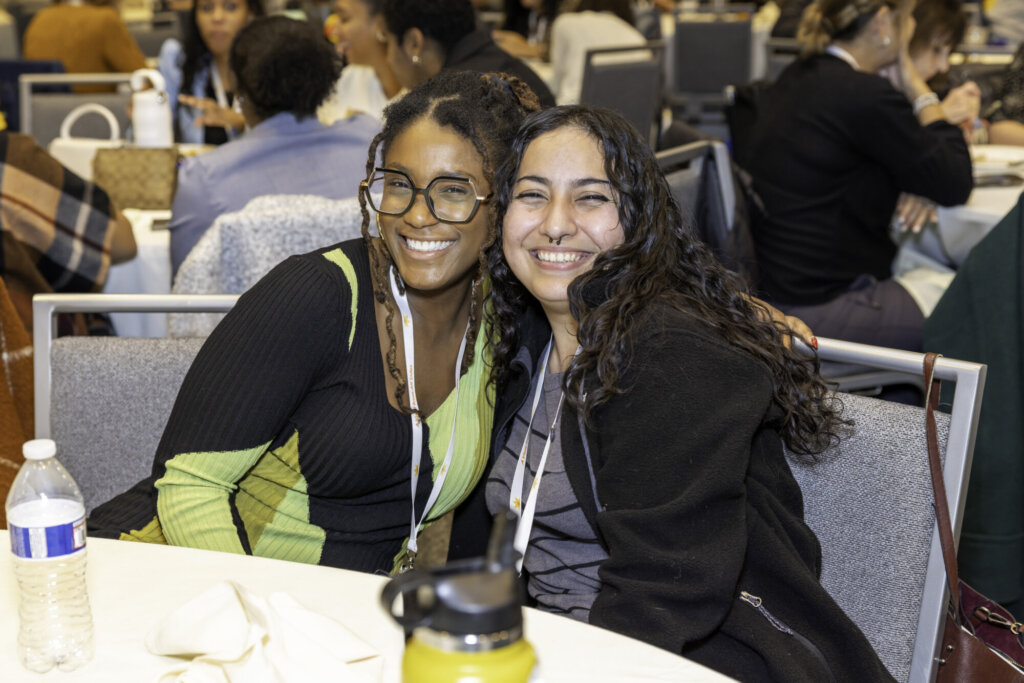 Two attendees smiling in the ballroom.