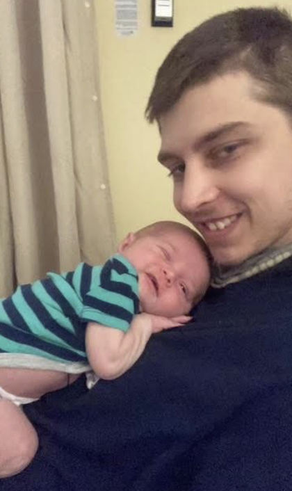 Baby laying on Andrew's chest smiling