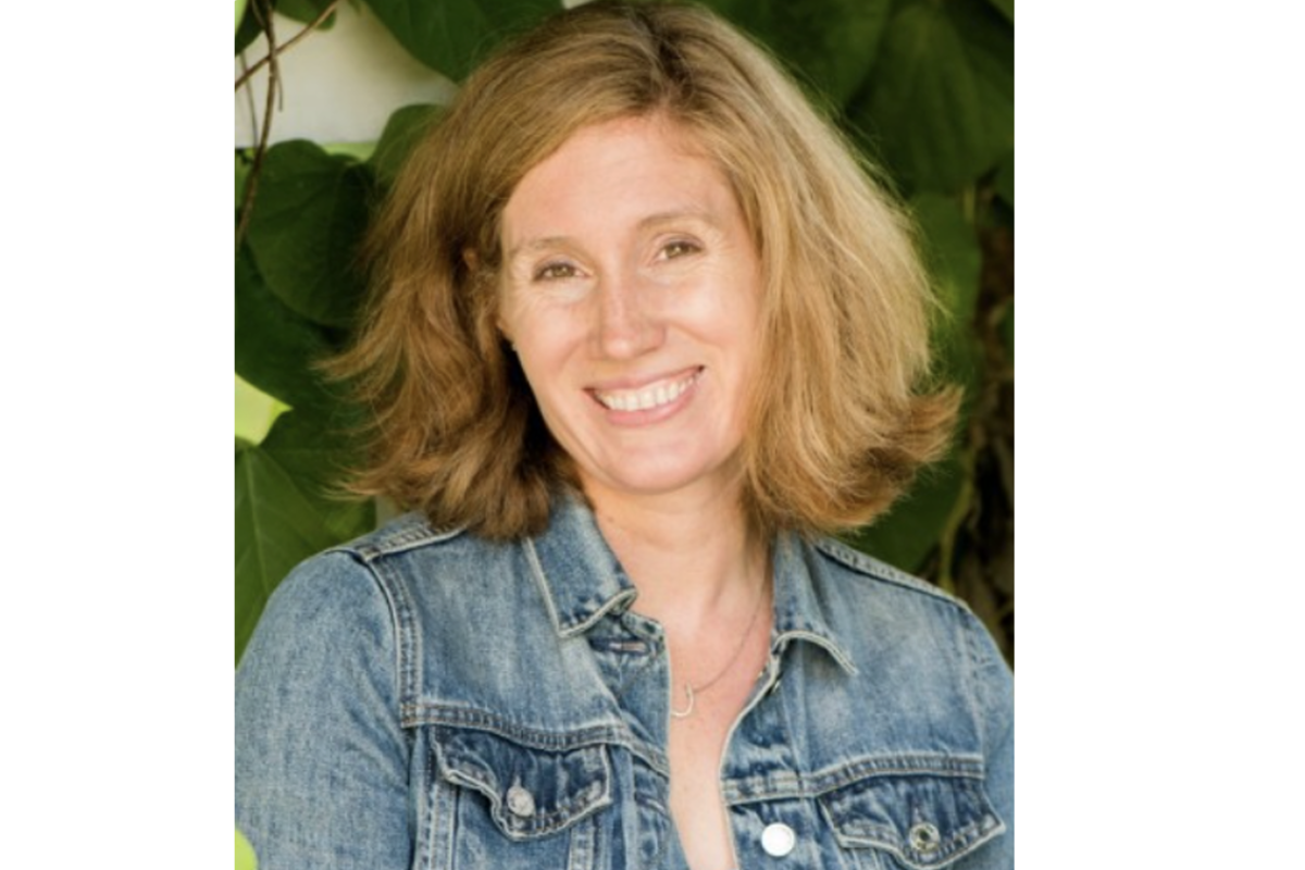 Sarah Kennedy McPhee, MPH, with shoulder-length light brown hair and a blue denim jacket, smiles at the camera. Green leaves and sunlight are visible in the background.