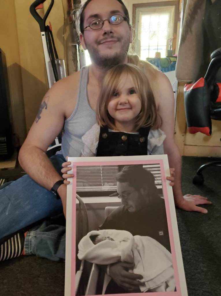Damien and his daughter with a childhood photo from when she was born