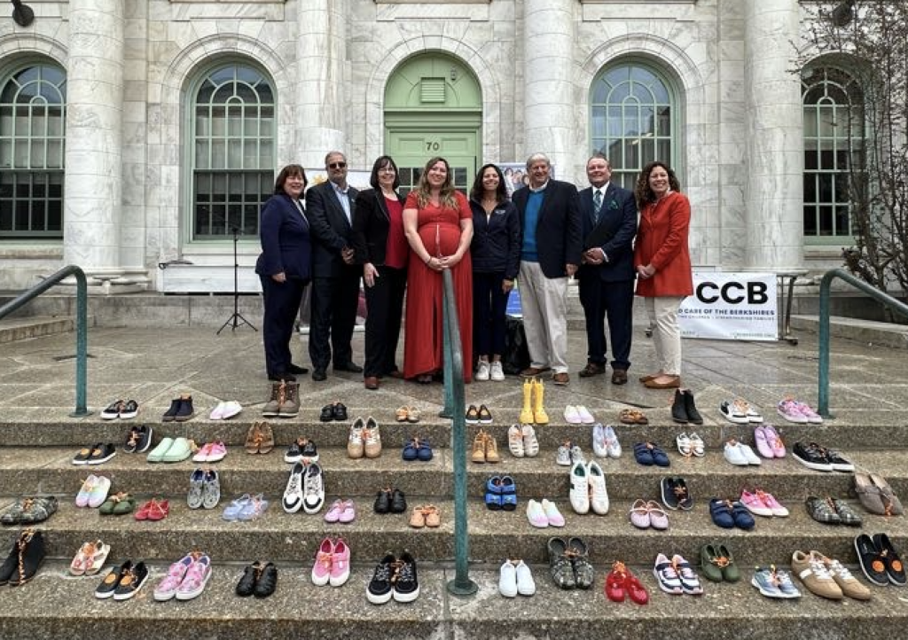 Speakers from the event lined up behind a display of childrens' shoes